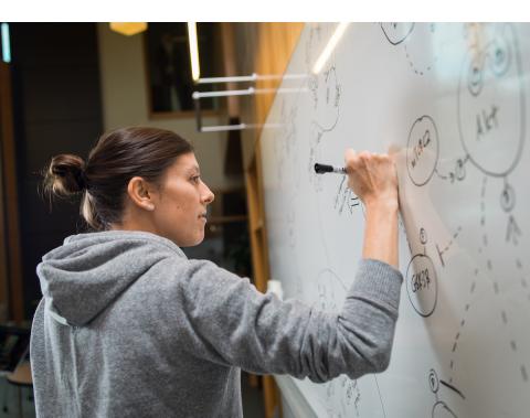 student at whiteboard solving math problem