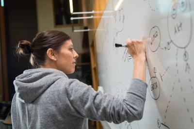 student at whiteboard solving math problem